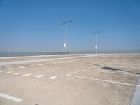 a empty parking lot with lines painted on it and a large sky over the ocean