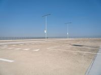 a empty parking lot with lines painted on it and a large sky over the ocean