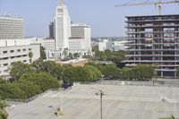 an empty parking lot in front of some tall buildings with palm trees in the foreground