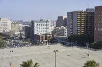 an empty parking lot in front of some tall buildings with palm trees in the foreground