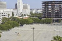 an empty parking lot in front of some tall buildings with palm trees in the foreground