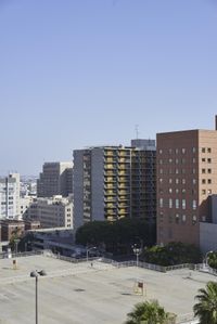 an empty parking lot in front of some tall buildings with palm trees in the foreground