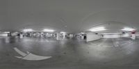 the fish eye lens captures a empty parking lot full of cars, and another person wearing a coat