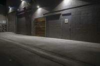 an empty parking lot with a sidewalk and large garage doors at night or day in the middle of winter