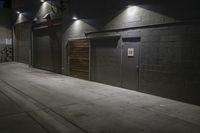 an empty parking lot with a sidewalk and large garage doors at night or day in the middle of winter