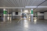 large empty parking spaces in an empty and empty mall garage area with green and white pillars