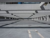 an empty parking lot covered in lots of columns and light posts with a street sign on one corner