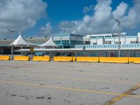 an empty parking lot filled with lots of buildings and trucks in the background of a cloudy blue sky