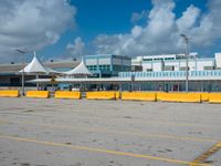 an empty parking lot filled with lots of buildings and trucks in the background of a cloudy blue sky