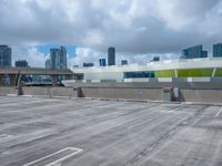 an empty parking lot with a parking garage below it in a big city, with a skyline visible in the background