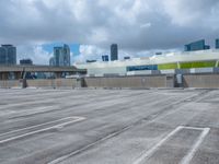 an empty parking lot with a parking garage below it in a big city, with a skyline visible in the background