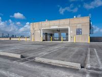 empty parking lot with a sky background and large windowed doors and a ramp leading to it