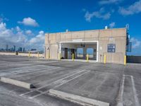 empty parking lot with a sky background and large windowed doors and a ramp leading to it