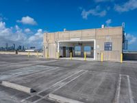 empty parking lot with a sky background and large windowed doors and a ramp leading to it