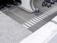 an empty parking lot with parking meters and parked cars visible in the background, looking down on the empty lot
