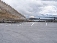 an empty parking lot by a mountain, with a motorcycle on one side and the other side painted black and white