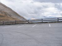 an empty parking lot by a mountain, with a motorcycle on one side and the other side painted black and white