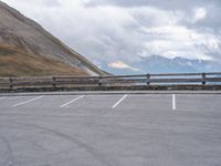 an empty parking lot by a mountain, with a motorcycle on one side and the other side painted black and white