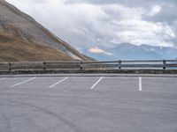 an empty parking lot by a mountain, with a motorcycle on one side and the other side painted black and white