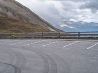 an empty parking lot by a mountain, with a motorcycle on one side and the other side painted black and white