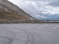 an empty parking lot by a mountain, with a motorcycle on one side and the other side painted black and white