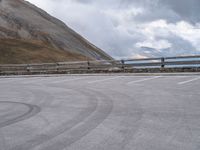 an empty parking lot by a mountain, with a motorcycle on one side and the other side painted black and white