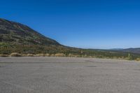a bike sitting on top of an empty parking lot with mountains in the background and a blue sky