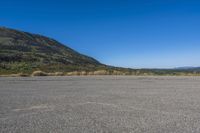 a bike sitting on top of an empty parking lot with mountains in the background and a blue sky
