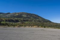 a bike sitting on top of an empty parking lot with mountains in the background and a blue sky