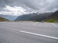 the empty parking lot is in front of the mountains on the cloudy day there are no cars