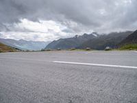 the empty parking lot is in front of the mountains on the cloudy day there are no cars