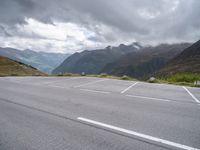 the empty parking lot is in front of the mountains on the cloudy day there are no cars