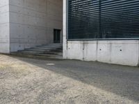 an empty parking lot near the back of a building with a window, door and stair