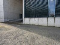 an empty parking lot near the back of a building with a window, door and stair