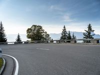 the parking lot for the motorcyclist is empty near trees and buildings, but it has no roads