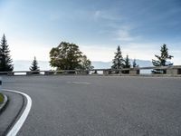 the parking lot for the motorcyclist is empty near trees and buildings, but it has no roads