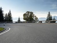 the parking lot for the motorcyclist is empty near trees and buildings, but it has no roads