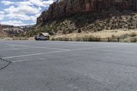 an empty parking lot next to the cliffs of a large rock formation and a parking meter on the opposite side