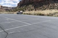 an empty parking lot next to the cliffs of a large rock formation and a parking meter on the opposite side