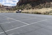 an empty parking lot next to the cliffs of a large rock formation and a parking meter on the opposite side