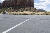 an empty parking lot next to the cliffs of a large rock formation and a parking meter on the opposite side