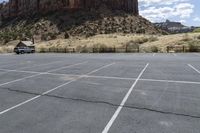 an empty parking lot next to the cliffs of a large rock formation and a parking meter on the opposite side