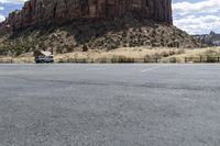 an empty parking lot next to the cliffs of a large rock formation and a parking meter on the opposite side