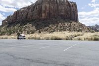 an empty parking lot next to the cliffs of a large rock formation and a parking meter on the opposite side