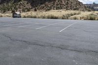 an empty parking lot next to the cliffs of a large rock formation and a parking meter on the opposite side