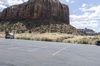 an empty parking lot next to the cliffs of a large rock formation and a parking meter on the opposite side