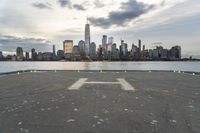 an empty parking lot in front of a city skyline on a hazy day by the water