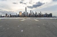 an empty parking lot in front of a city skyline on a hazy day by the water