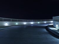 an empty parking lot at night with a sky background, and several lights on a walkway