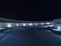 an empty parking lot at night with a sky background, and several lights on a walkway